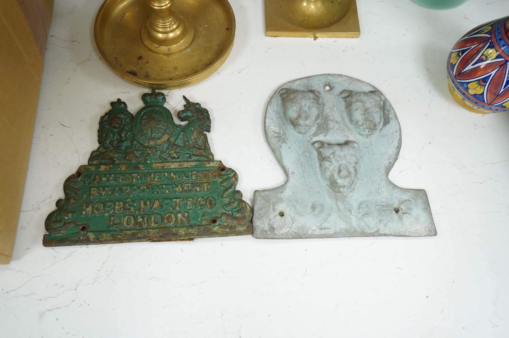 Two fire marks and a collection of brass candlesticks, tallest 25.5cm